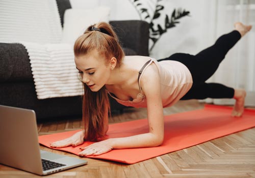 Девушка делает фитнес-тренировку дома перед ноутбуком