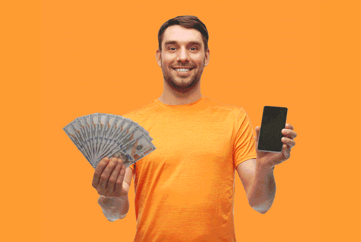 Мужчина держит в руках деньги и смартфон