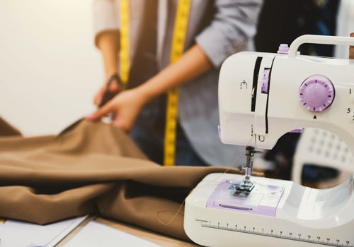 Портной-модельер раскраивает ткань на швейной машинке
