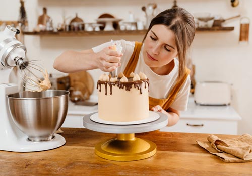 Женщина-кондитер готовит дома торт с кремом