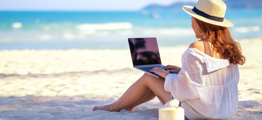 Девушка работает за ноутбуком на красивом пляже